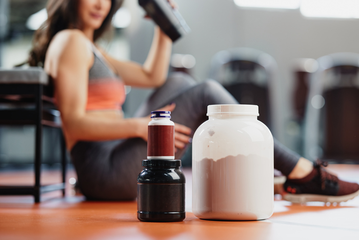 Selective focus on supplements and protein power in gym with a sportswoman.